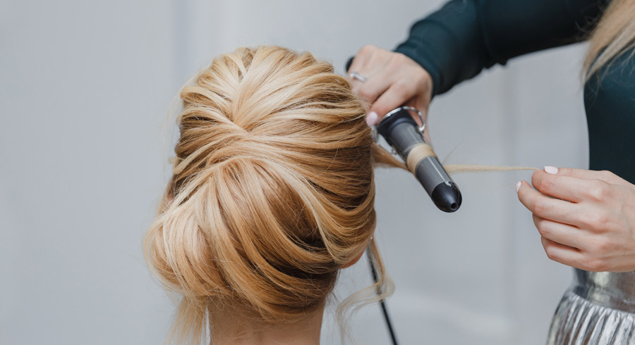 Closeup of professional hairdresser hands doing beauty hairstyle a la french twist